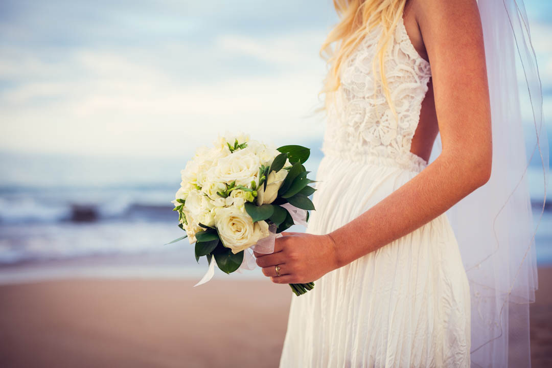 beautiful bride standing by the beach at sunset